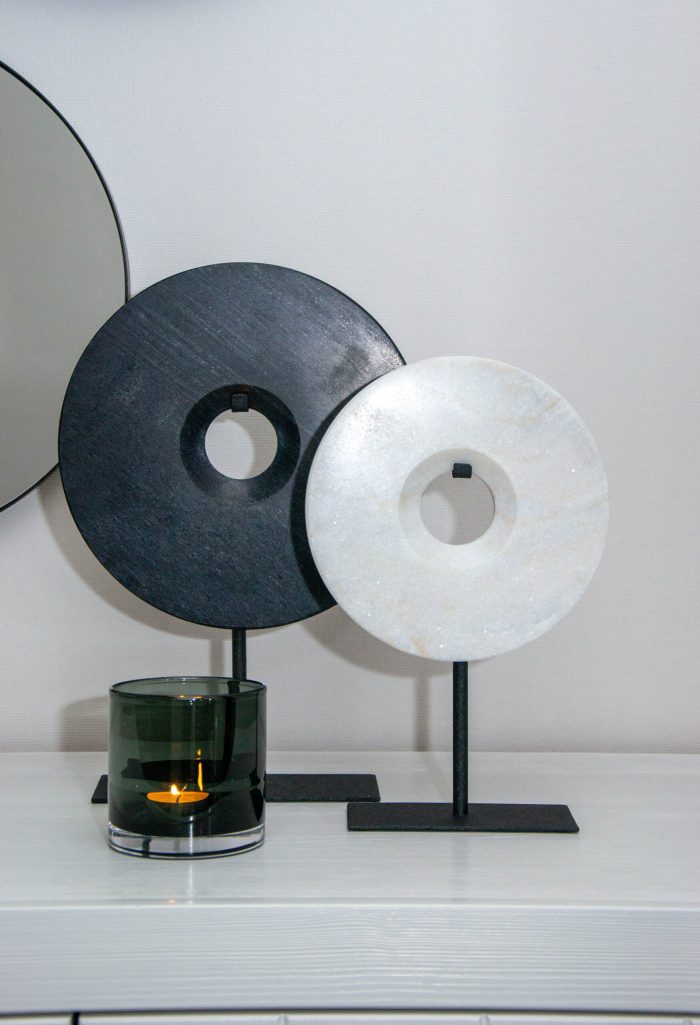 Bob Ornament Puck Wit – ronde marmeren schijf op zwarte standaard, naast de variant Bob ornament Puck Zwart