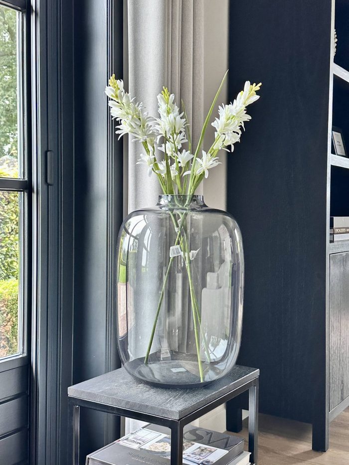 Vaas Kara Grey van Vase The World in diepgrijs glas, gestyled met takken op een houten tafel