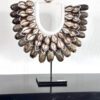 Luma schelpenketting op zwarte standaard – handgemaakt ornament met bruin- en natureltinten, perfect voor een werelds of rustig interieur.