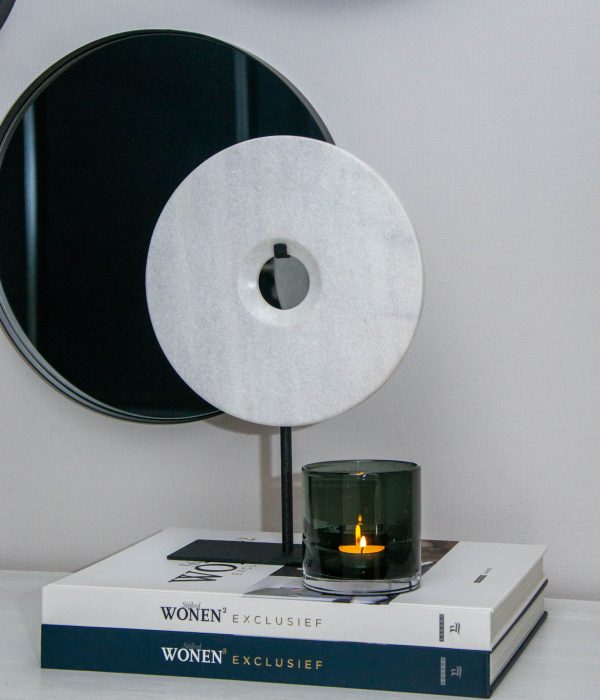 Bob Ornament Puck Wit – ronde marmeren schijf op zwarte standaard, gestyled op woonboeken met glazen windlicht