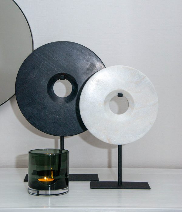 Bob Ornament Puck Wit – ronde marmeren schijf op zwarte standaard, naast de variant Bob ornament Puck Zwart
