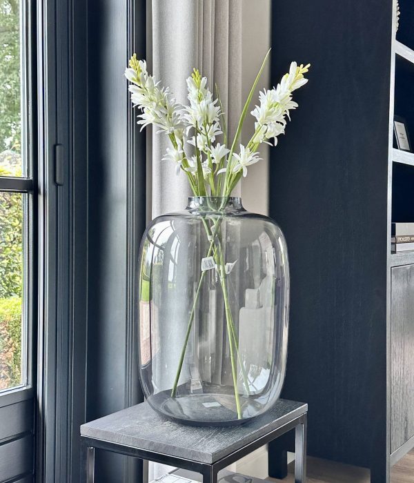 Vaas Kara Grey van Vase The World in diepgrijs glas, gestyled met takken op een houten tafel