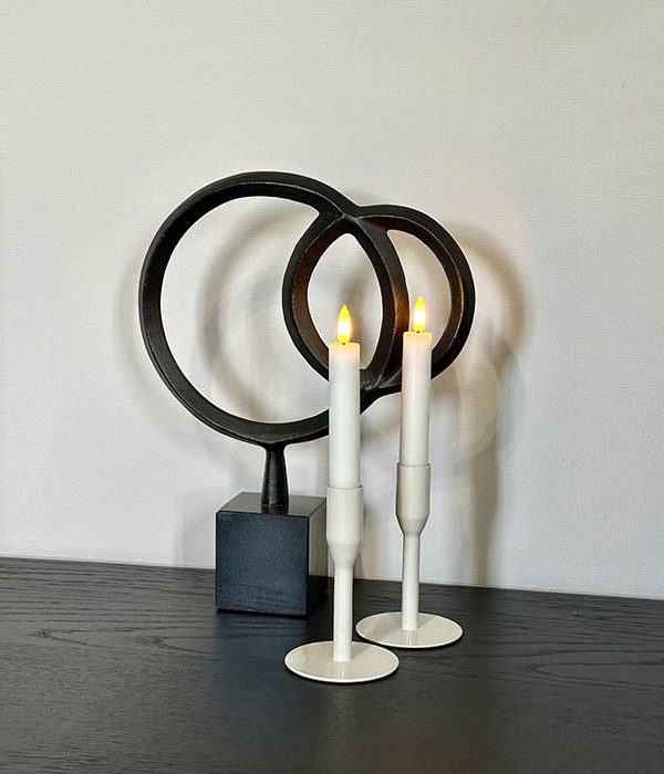 Set van twee beige metalen kandelaars als sfeervolle decoratie op een houten dressoir.