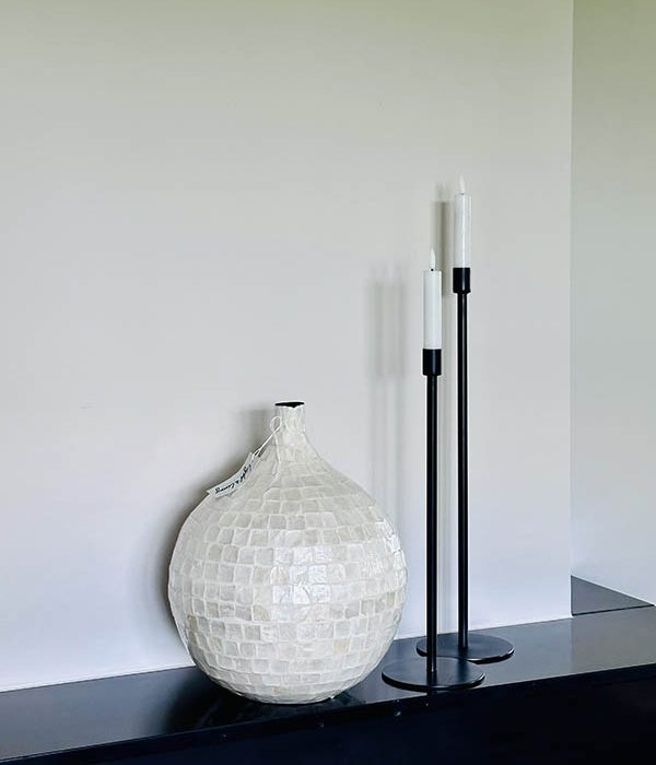 Ronde bamboe vaas Elorza Cream met glanzende schelptegels naast zwarte kandelaars