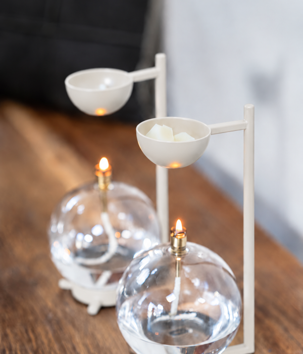 Twee beige Peri Living geurbranders met glazen olielampen op een houten tafel