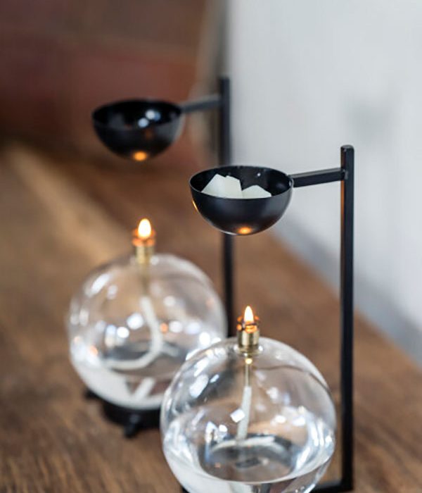 Witte waxmelts in een zwarte geurbrander boven een glazen olielamp