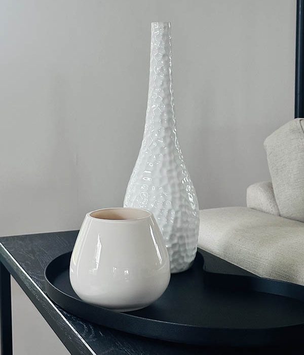 Vase The World Kaarshouder Tasman XS Ivory – Beige, glazen waxinelichthouder op zwart dienblad naast lichte bank