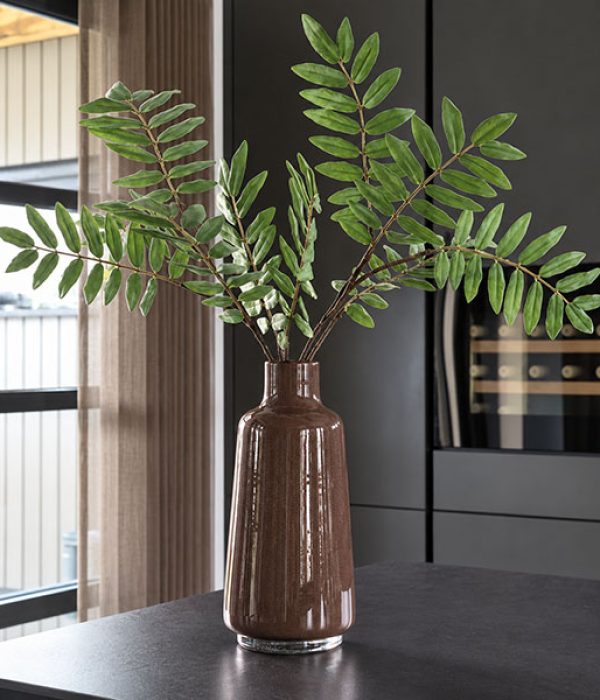 Donkerbruine Vaas Jana Elite met groene takken in een modern interieur