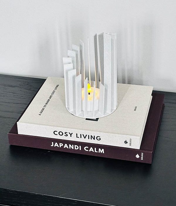 Wit metalen windlicht Bali Linea met open structuur op boeken